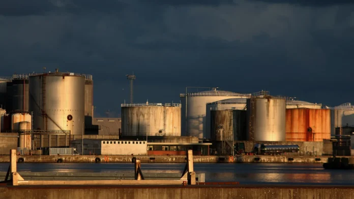 The risk to oil prices in mid-2026 is no longer a war premium — it is a peace dividend. The framework agreement between Washington and Tehran, due to be signed on June 19, 2026, pairs a $300 billion private investment fund for Iran with the immediate resumption of Iranian oil exports and the reopening of the Strait of Hormuz, the waterway that carries roughly a fifth of the world's daily crude supply. The market read the signal instantly: West Texas Intermediate (WTI) crude fell 4.8% to $80.75 a barrel and Brent dropped 4.7% to $83.17 on June 16, with Brent now down nearly 40% from its conflict peak (NBC News). With Iranian barrels returning and the geopolitical premium draining away, the credible 2026 path points toward $70 Brent — and the move matters far beyond the oil pit.
Here is the synthesis most single-asset coverage misses: this is one geopolitical event repricing four markets at once. The same de-escalation that is pulling oil lower is feeding a risk-on bid into equities and crypto — Bitcoin rebounded toward $67,000 on the breakthrough — while easing the energy-driven inflation premium that had pushed long-dated bond yields higher. For a trading desk, the $300 billion Iran deal is not an energy story; it is a correlated unwind of the entire war trade. That cross-asset linkage, not the oil headline alone, is what makes the next 60 days unusually consequential.
<strong>Quick Take:</strong> The $300 billion US-Iran deal reopens the Strait of Hormuz and restores Iranian oil exports, sending WTI to $80.75 and Brent to $83.17. Goldman Sachs cut its Q4 Brent forecast to $80 and Fitch sees prices easing toward $70 by September — but thin OPEC+ spare capacity keeps the floor higher than outright bears expect.
<strong>Key Facts:</strong>
The US-Iran framework, due to be signed June 19, 2026, includes a $300 billion private investment fund, over half already committed — <a href="https://cryptobriefing.com/iran-deal-300b-private-fund/">Crypto Briefing</a>
WTI fell 4.8% to $80.75 and Brent 4.7% to $83.17 on June 16, 2026; Brent is down nearly 40% from its conflict peak — <a href="https://www.nbcnews.com/business/markets/oil-prices-iran-deal-hormuz-doubts-rcna350087">NBC News</a>
The Strait of Hormuz carries roughly 20% of the world's daily oil supply — <a href="https://www.bloomberg.com/news/articles/2026-06-17/iran-to-gain-major-financial-relief-under-interim-deal-with-us">Bloomberg</a>
Goldman Sachs cut its Q4 2026 Brent forecast to $80 from $90 after the deal — <a href="https://www.cnbc.com/2026/06/16/goldman-cuts-oil-forecast-as-hormuz-deal-brings-forward-supply-recovery.html">CNBC</a>
Fitch Ratings sees Brent at $100–110 in May–July, $80 in August, and about $70 from September — <a href="https://www.tribuneindia.com/news/2026-forecast/fitch-projects-brent-crude-oil-at-87-bbl-average-in-2026-expects-prices-to-ease-after-july-if-hormuz-reopens">Fitch via The Tribune</a>
OPEC+ spare capacity is roughly 2.5 million barrels per day after the UAE's exit, keeping the market structurally tight — IEA / OPEC data
What's actually happening and why
The mechanism is supply, and specifically the unblocking of it. During the 2026 conflict, the threat to the Strait of Hormuz — the chokepoint through which around a fifth of global crude moves — stripped Iranian barrels from the market and priced in a worst-case closure. Brent spiked above $100 as a result. The framework deal reverses both effects at once: it restores Iran's right to sell oil immediately and reopens the strait, with US President Donald Trump confirming the lifting of the naval blockade on Iranian ports ahead of the June 19 signing.
The real-world analogy is a dammed river suddenly released. For weeks the market priced barrels as if they might never arrive; now traders are pricing the flood. Goldman Sachs expects tanker traffic through Hormuz to recover fully by the end of July, which is why banks have moved quickly to cut forecasts. The 60-day initial opening window gives shippers and refiners a concrete timeline to reroute and restock. For the technical picture behind the move, see our analysis of how <a href="https://financefeeds.com/wti-oil-breakdown-signals-further-losses-as-bears-target-70/">WTI's breakdown signals further losses as bears target $70</a>.
The bank that called the supply shock is now calling the relief. "As the last tankers that crossed the Strait of Hormuz before the war are reaching their destination, concerns about potential oil shortages are rising," wrote Daan Struyven, Head of Oil Research at Goldman Sachs, capturing the squeeze that has now begun to unwind (<a href="https://www.cnbc.com/2026/06/16/goldman-cuts-oil-forecast-as-hormuz-deal-brings-forward-supply-recovery.html">CNBC</a>).
Industry response: banks slash forecasts, OPEC+ holds the floor
The sell-side response has been swift and one-directional. Goldman Sachs cut its fourth-quarter 2026 Brent forecast to $80 a barrel from $90; Citi trimmed its Brent target as Hormuz fears eased; and Fitch Ratings mapped a glide path from today's mid-$80s toward $70 by September. The common thread is timing: with tanker flows expected to normalise by end-July, the war premium has no reason to persist into the autumn. The scale of the repricing is already visible — Brent's near-40% retreat from its conflict peak has effectively erased the entire war premium in a matter of weeks, one of the sharpest geopolitical unwinds the crude market has seen, and it happened before a single additional Iranian barrel has cleared the strait under the new terms.
But the supply side is not a clean bear story, and this is where the consensus oversimplifies. OPEC+ spare capacity sits at roughly 2.5 million barrels per day following the UAE's exit from the group's quota framework — historically thin, and a structural reason the market stays tighter than it was before the conflict. OPEC+ output had already fallen by about 1.74 million barrels per day in April, and OPEC's May monthly report cut its 2026 global demand-growth forecast to 1.17 million barrels per day. In other words, Iranian barrels return into a market where the cartel has limited cushion and demand is softening — a combination that argues for a managed decline toward $70 rather than a collapse. Fitch's Angelina Valavina, a managing director at the agency, has framed the easing as contingent on the strait actually staying open, not a foregone conclusion. For the macro read on how the thaw is reshaping currencies and rates, see our <a href="https://financefeeds.com/global-fx-market-summary-us-iran-diplomatic-thaw-shifting-monetary-policy-and-market-sentiment-realignment-15-june-2026/">US-Iran diplomatic thaw market summary</a>.
Market impact and the cross-asset data
From a June 16 close of $80.75 WTI and $83.17 Brent, the named forecasts converge on a lower path. Here is how the scenarios stack up:
ScenarioBrent pathTrigger
<strong>Base (deal holds)</strong>$80 Aug → ~$70 SeptHormuz stays open, Iranian exports normalise (Fitch, Goldman)
<strong>Bear (supply glut)</strong>Mid-$60s 2H26OPEC+ unwinds cuts as Iran returns; demand stays soft
<strong>Bull (deal collapses)</strong>$100–110+Strait re-closes or nuclear talks break down
<em>Sources: Goldman Sachs and Fitch Ratings forecasts via CNBC and The Tribune; spot prices NBC News, June 16, 2026.</em>
The data synthesis that matters for a markets desk is the correlation map. Oil's 40% retreat from its conflict peak is not happening in isolation: it is the energy leg of a broader risk-on reset. As the inflation premium baked into crude unwinds, the pressure on long-dated bond yields eases, and risk assets that had been discounted for war — equities and crypto alike — catch a bid. Bitcoin's rebound toward $67,000 on the breakthrough is the same trade expressed in a different asset, as we covered in <a href="https://financefeeds.com/geopolitical-breakthrough-sparks-risk-on-rally-as-bitcoin-rebounds-toward-67000/">how the geopolitical breakthrough sparked a risk-on rally</a>. The practical takeaway: a desk hedging oil exposure should be watching Bitcoin and the bond curve as correlated expressions of the same Iran headline, because they will move together if the deal holds — and reverse together if it breaks.
The bond-market leg of this trade deserves its own attention, because it has the longest tail. The 2026 conflict added an energy-driven inflation premium to long-dated yields at precisely the moment a hawkish Federal Reserve was already keeping the front end elevated; crude's surge above $100 fed directly into breakeven inflation expectations. As Brent retraces toward $70, that premium deflates, which removes one upward pressure on the long bond even if it does not reverse the structural term-premium story. The interplay is subtle: lower oil is disinflationary at the margin, which can paradoxically revive the rate-cut expectations the Fed has been resisting, steepening the curve through the front rather than the back. For the mechanics of how these yield dynamics resolve into year-end, see our breakdown of <a href="https://financefeeds.com/government-bond-returns-2026-year-end-prediction-math/">government bond returns and the 2026 year-end prediction math</a>. For energy-exposed brokers and macro funds, the lesson of the past month is that a single chokepoint headline can dominate every asset on the screen at once.
The geopolitical and regulatory tension
The deal's durability is the single largest risk to every forecast above, and it is far from settled. The agreement is explicitly interim: sanctions relief is tied to "clear, verifiable steps by Iran on its nuclear programme," and the hardest questions — enrichment, inspections, the fate of frozen assets — are deferred to later negotiation. The strait reopening is reported to run for an initial 60 days, a window, not a permanent settlement.
The $300 billion fund itself is politically contested in Washington. CNN has framed it as "Trump's $300 billion problem," drawing comparisons to the controversy over sanctions relief under the 2015 nuclear accord, and domestic opposition could complicate implementation even after signing. For oil, that political fragility cuts both ways: it caps how far bears can run the price down, because any headline suggesting the deal is wobbling will instantly restore a risk premium. This is why Fitch and Goldman both condition their lower targets on the strait staying open — the base case is not "oil falls to $70," it is "oil falls to $70 if the peace holds." Compliance and treasury teams at trading firms will be watching the sanctions-relief mechanics closely, because the speed at which Iranian crude can be legally cleared, financed and insured determines how fast the barrels actually hit the market. A deal on paper moves oil; a deal that clears the banking and insurance plumbing moves it further.
What happens next: three predictions
First, expect Brent to grind toward the $70s through the third quarter if the strait stays open, tracking the Fitch and Goldman glide paths, with tanker normalisation by end-July as the key confirming signal. The move will be a managed decline rather than a crash, because OPEC+ has the incentive and — barely — the spare capacity to defend a floor.
Second, expect volatility to stay elevated around every nuclear-negotiation headline. With the deal interim and the 60-day window finite, each milestone is a binary risk event that can restore or erase the war premium overnight. The options market will keep pricing fat tails even as spot drifts lower.
Third, expect the cross-asset correlation to persist: as long as the Iran file dominates the macro tape, oil, bond yields and risk assets including Bitcoin will trade as a single de-escalation theme. The forward-looking question is not simply how low oil goes — it is whether the $300 billion peace dividend proves durable enough to let the entire war trade fully unwind, or whether the first broken promise drags all four markets back the other way.
FAQ
<strong>How will the $300 billion US-Iran deal affect oil prices?</strong>
The deal restores Iranian oil exports and reopens the Strait of Hormuz, removing the war premium. WTI fell to $80.75 and Brent to $83.17 on June 16, 2026, and analysts at Fitch and Goldman Sachs see Brent easing toward $70–$80 through the second half of 2026 if the deal holds.
<strong>What is the $300 billion fund in the Iran deal?</strong>
It is a private investment fund designed to attract corporate capital into Iran, with more than half of the $300 billion already committed ahead of the June 19, 2026 signing. It is paired with the right to sell oil and eventual access to frozen assets as an economic incentive to end the conflict.
<strong>Why is the Strait of Hormuz so important for oil?</strong>
It carries roughly 20% of the world's daily crude supply. Its threatened closure during the 2026 conflict drove Brent above $100; its reopening under the deal is the main driver of the price decline.
<strong>How low could oil prices fall in 2026?</strong>
Fitch Ratings projects about $70 Brent from September, and Goldman Sachs sees $80 in the fourth quarter. A deeper bear case toward the mid-$60s is possible if OPEC+ unwinds production cuts as Iranian barrels return and demand stays soft.
<strong>What could push oil prices back up?</strong>
A collapse of the interim deal — a re-closure of the Strait of Hormuz or a breakdown in nuclear negotiations — would quickly restore the geopolitical premium and send Brent back toward $100–110, according to Fitch's price path.
<strong>How does the oil move affect Bitcoin and bonds?</strong>
The same de-escalation that lowers oil eases the energy-driven inflation premium, supporting risk assets and softening upward pressure on long-dated yields. Bitcoin rebounded toward $67,000 on the deal, trading as the same risk-on theme expressed in a different asset.
<strong>Will OPEC+ let oil prices fall sharply?</strong>
Unlikely without a fight. With spare capacity around 2.5 million barrels per day after the UAE's exit and 2026 demand growth cut to 1.17 million barrels per day, OPEC+ has both the incentive and the limited cushion to defend a floor, favouring a managed decline toward $70 over a collapse.
<em>This article is informational analysis only and is not financial, investment, or trading advice. Commodity, currency and crypto markets are highly volatile and can lose value rapidly; price forecasts are estimates, not guarantees, and past performance does not predict future results. Do your own research and consult a regulated financial adviser before making any investment decision.</em>